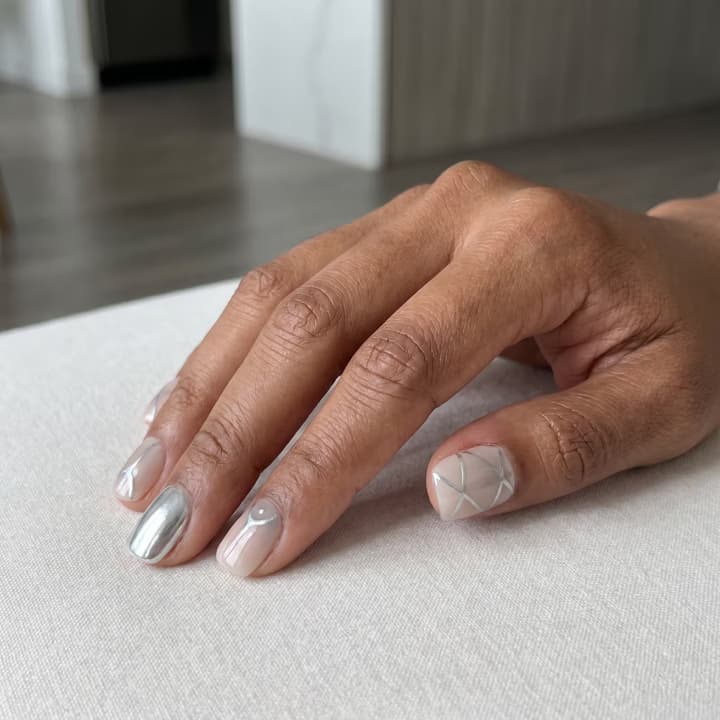 Medium-deep skin hand with short, minimal silver chrome press-on nails